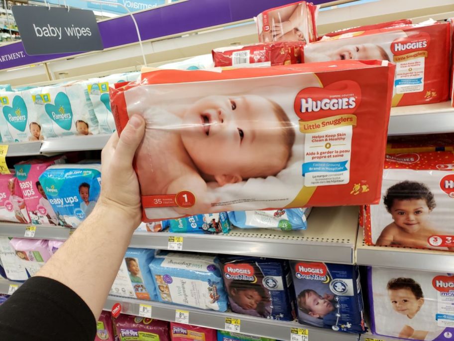 hand holding a pack of Huggies diapers