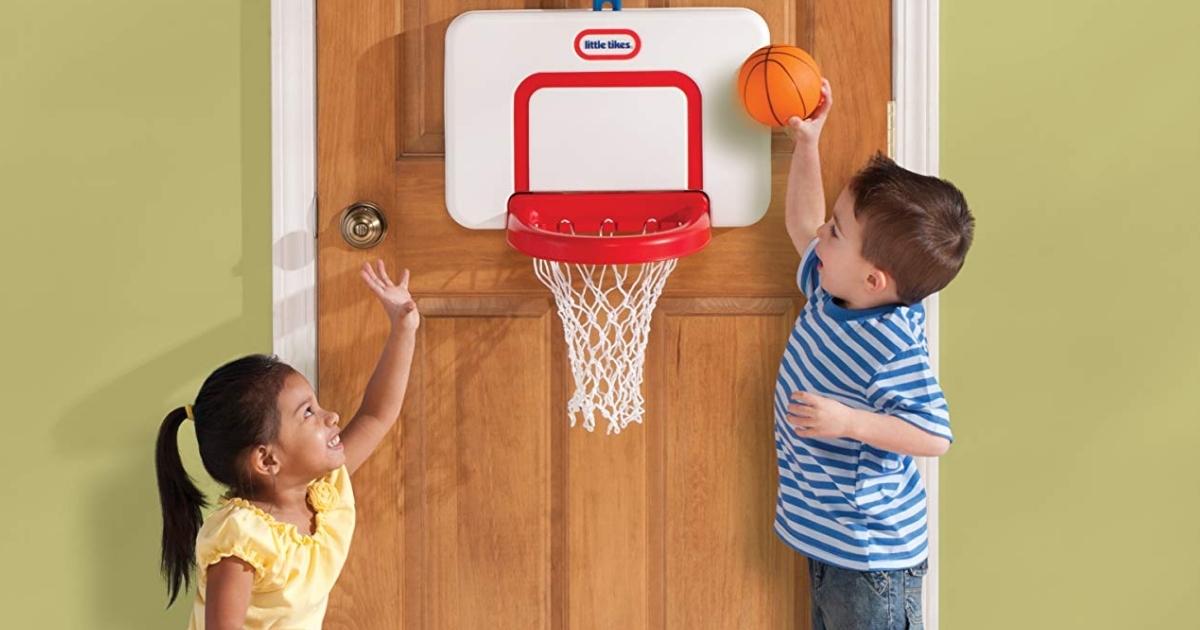 two kids playing with a little tikes basketball hoop set attached to a door