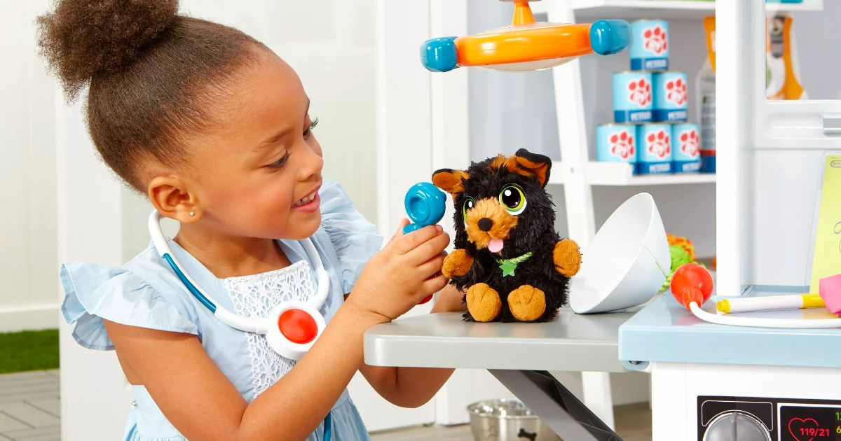a little girl examining a plush puppy toy as she plays with the Little Tikes My First Pet Checkup Set