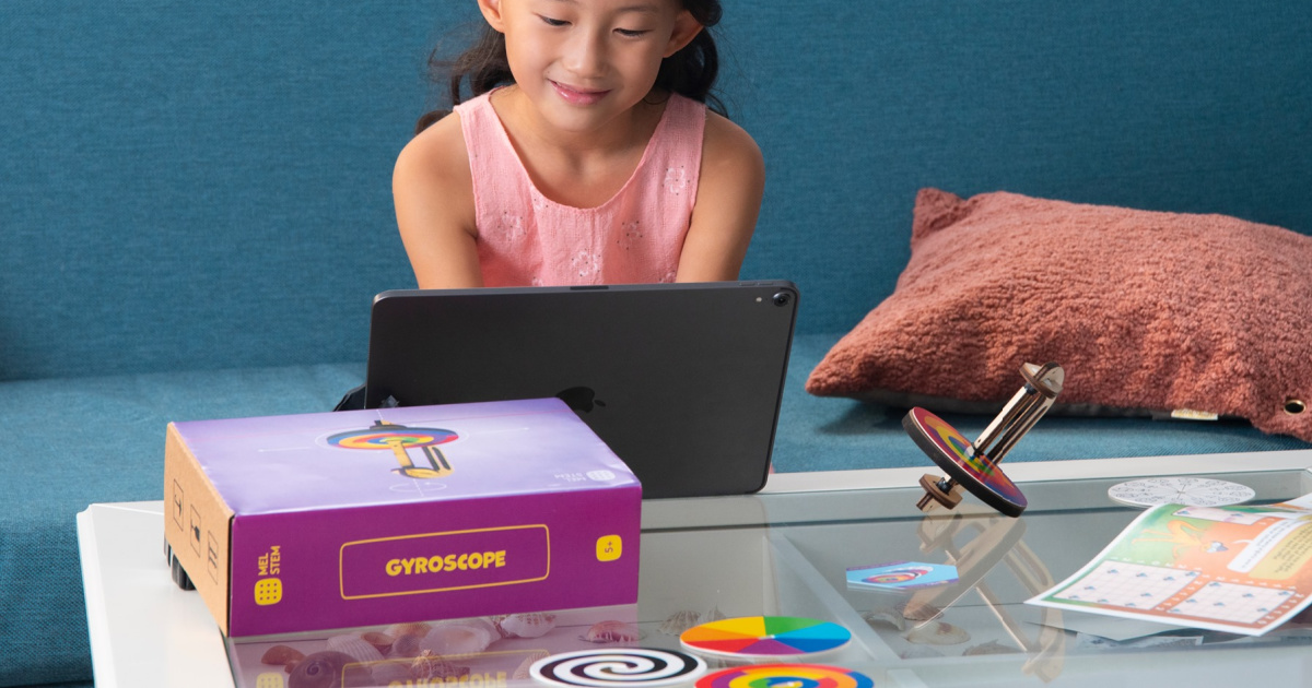 girl in front of laptop with science kit on table