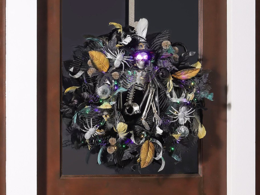 black and silver halloween wreath on door with skeleton in center