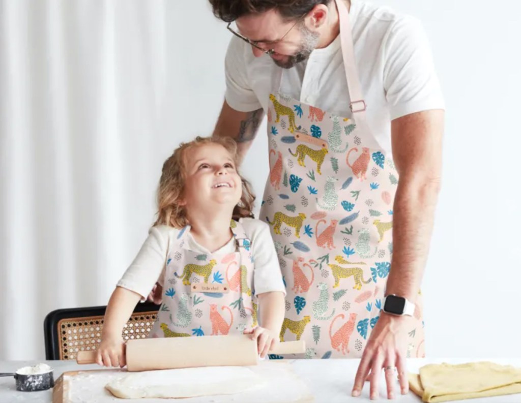 dad and girl smiling at each other rolling dough on countertop