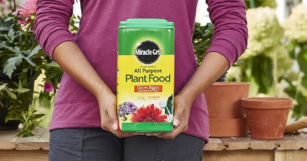 person in pinnk shirt holding box of plant food