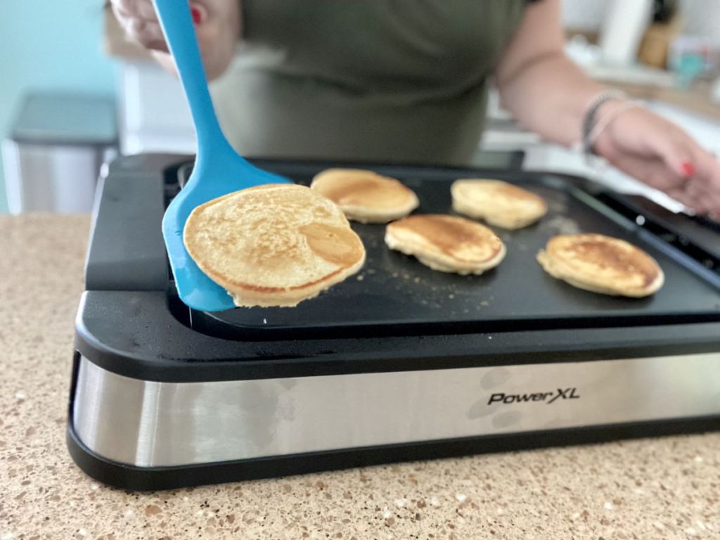 person flipping pancakes on a Power XL griddle