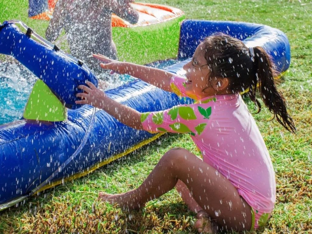 little girl playing with water gun built onto water slide
