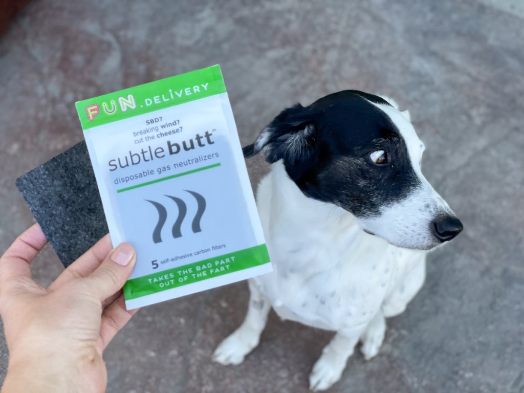 holding Subtle Butt pad and package with dog looking nervously away
