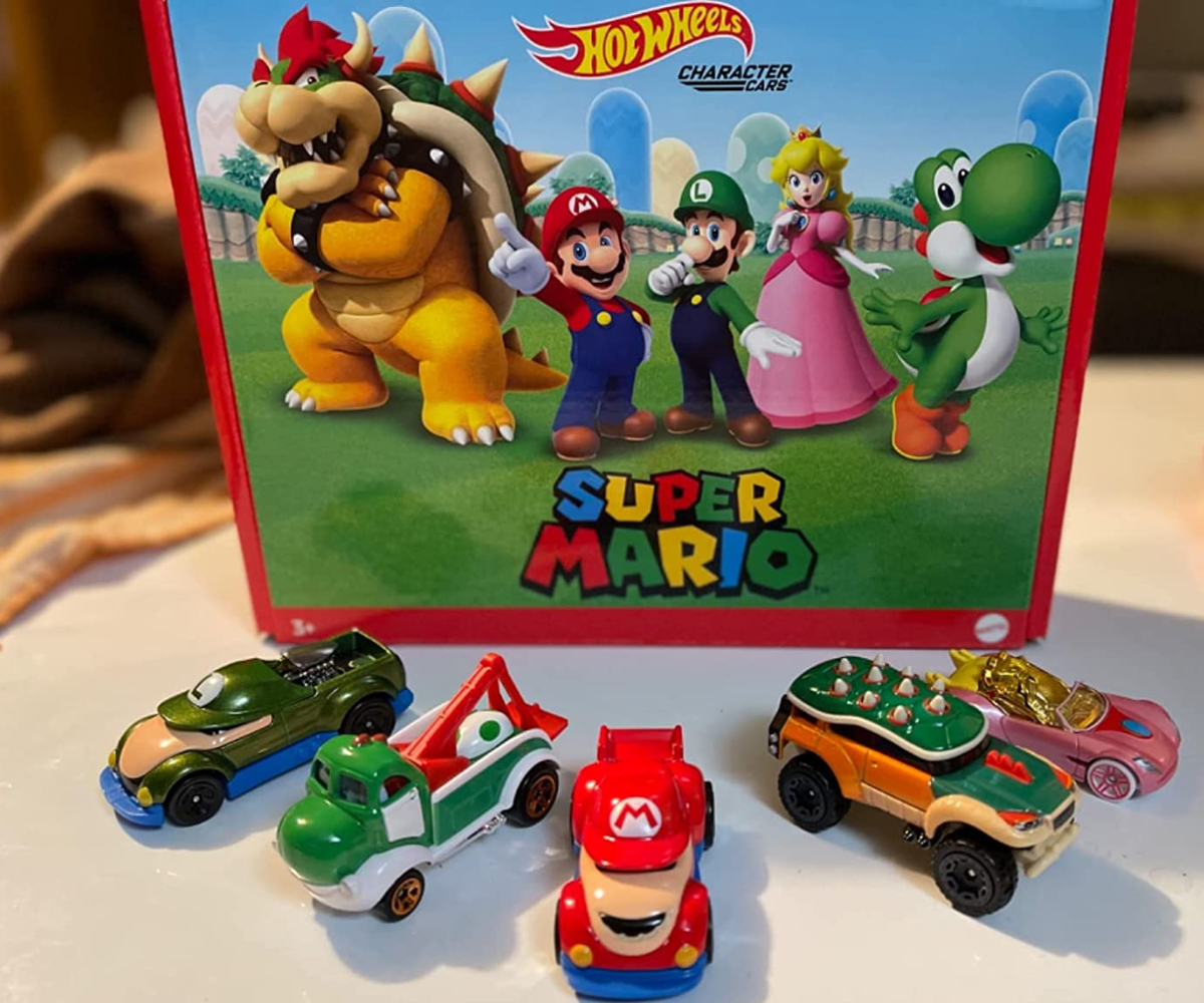 five Hot Wheels Super Mario cars displayed on a table in front of the packaging