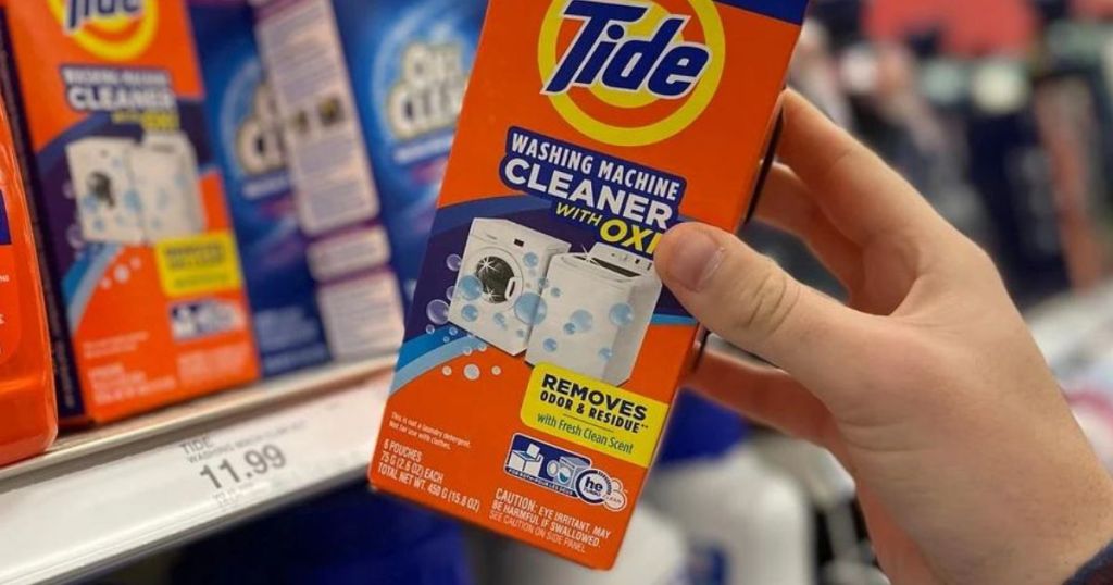 a hand holding a box of Tide washing machine cleaner 5pck