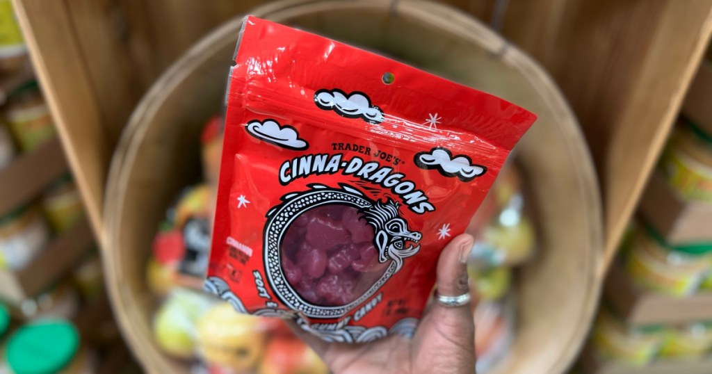 hand holding bag of red cinnamon dragon-shape candy in store