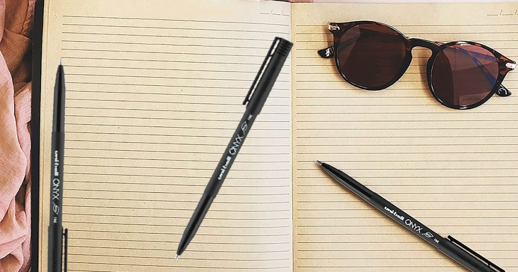 pens on sunglasses on open notebook