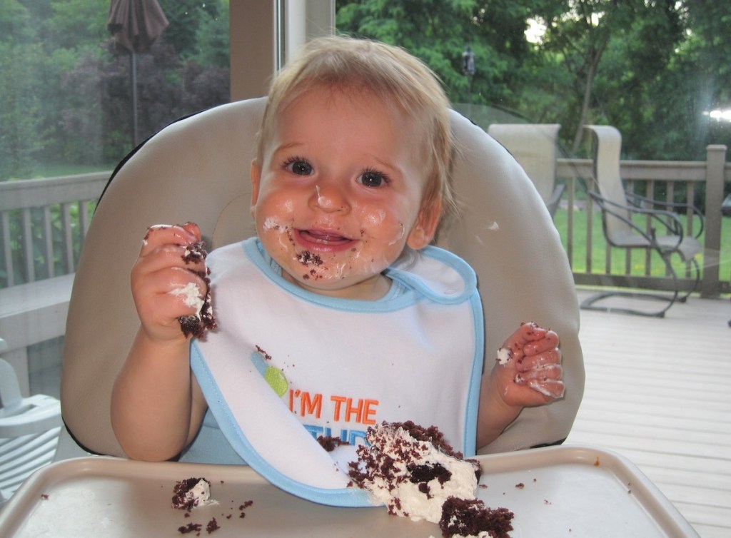 baby eating chocolate and icing in highchair