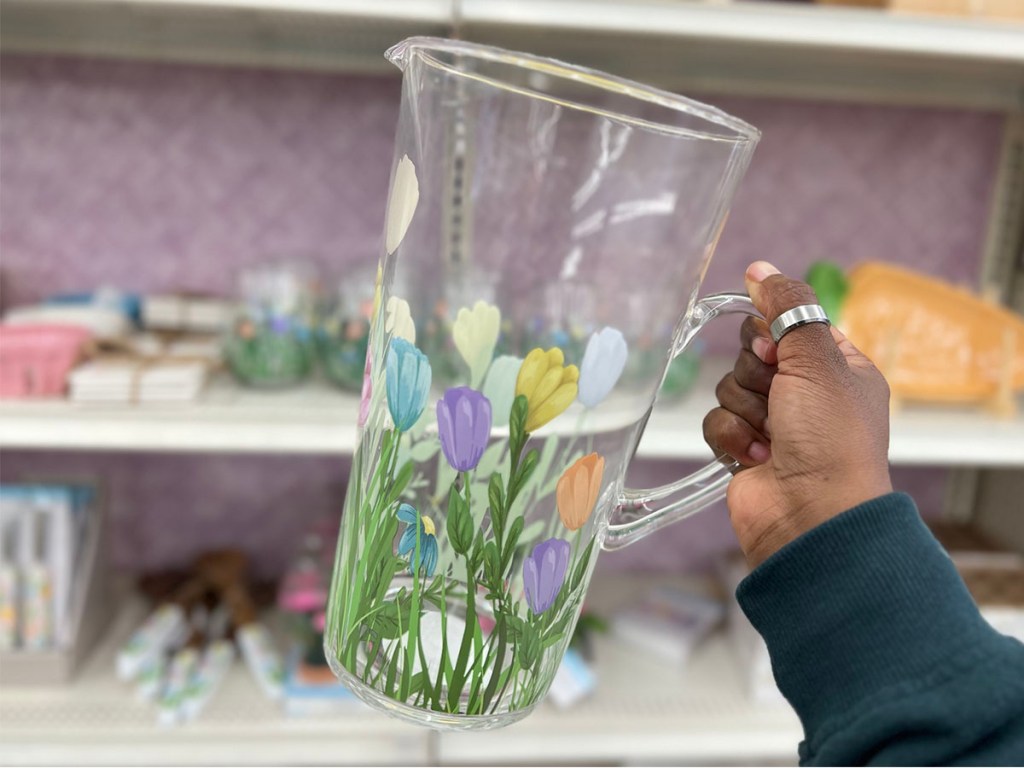 hand holding glass pitcher with flowers painted on it