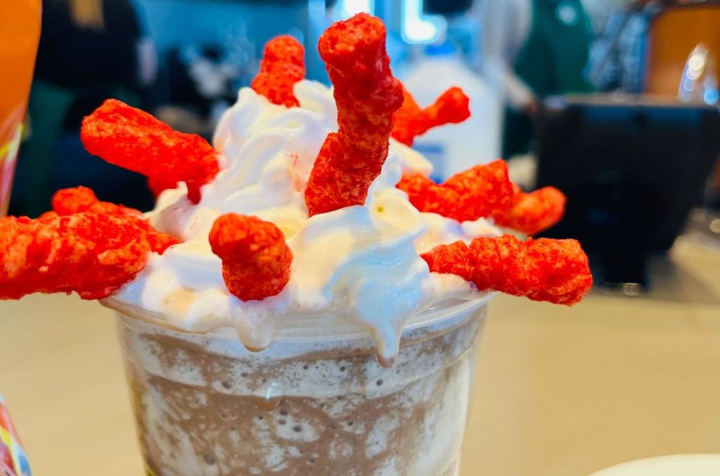 close up of starbucks drink with whipped cream and flamin hot cheetos