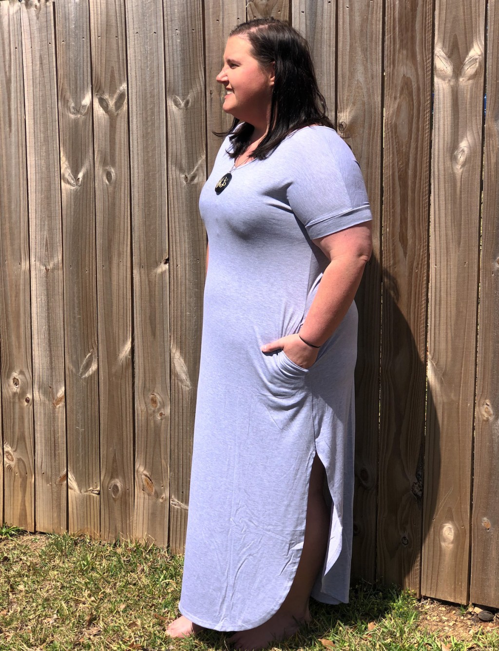 woman wearing gray maxi dress standing in front of fence