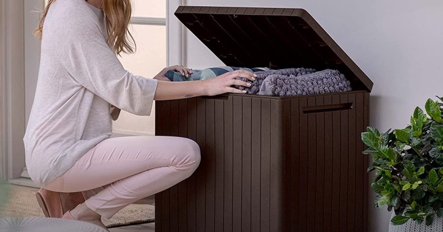 woman puting linens into brown storage box