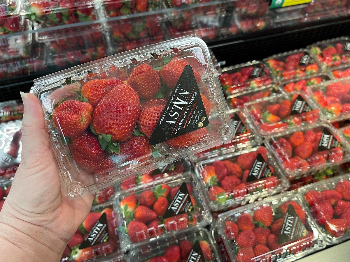 holding a 16-oz. clamshell package of straweberries