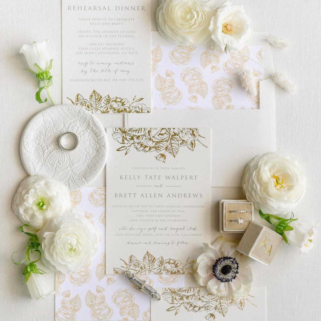 flatlay of wedding invitations and flowers on cream tablescape