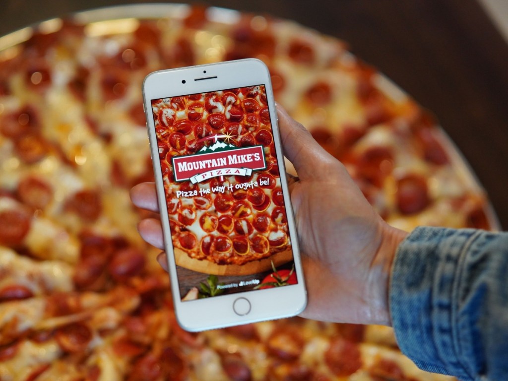 holding iPhone in front of pizza