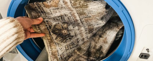 hand holding edge of vintage rug front front loading washing machine