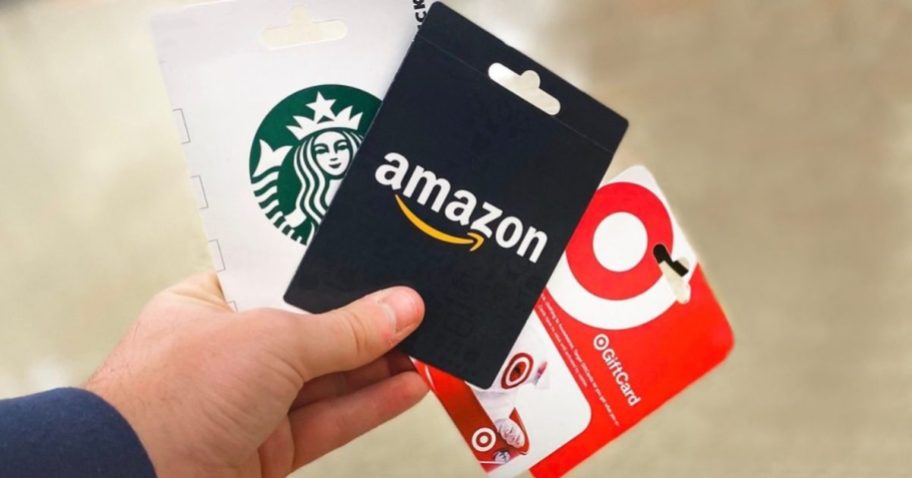 person holding Starbucks, Amazon and Target gift cards