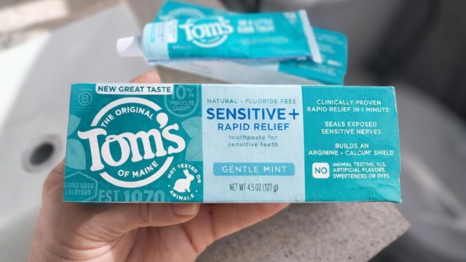 a mans hand holding a tube of toothpaste
