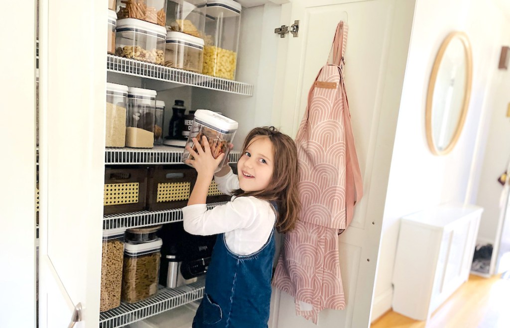 girl taking food storage organizer out of pantry