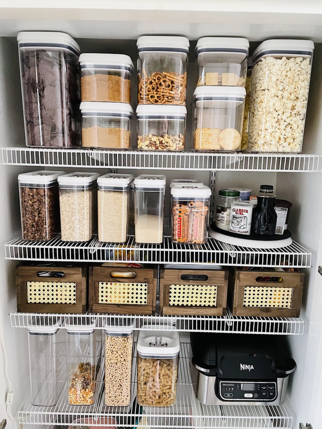 organized pantry with clear containers and rattan wood baskets