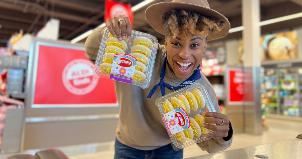 woman holding two packages of yellow frosted cookies in store