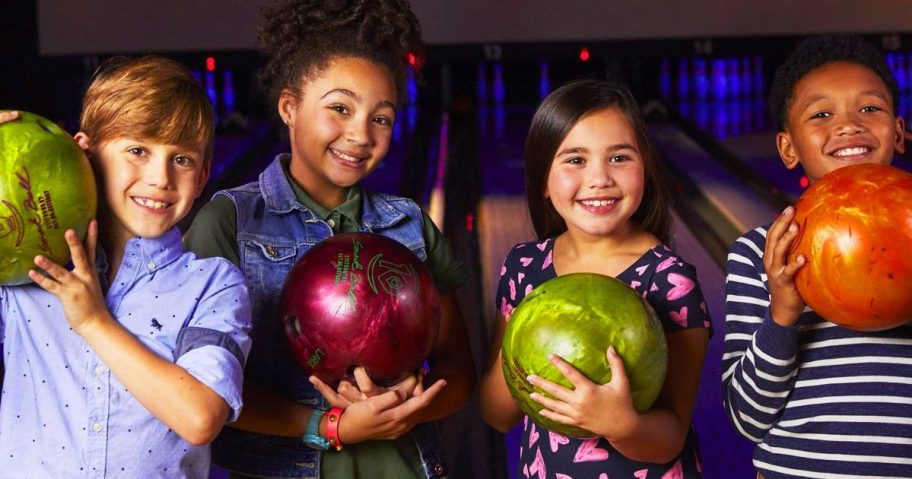 group of kids holding bowling balls