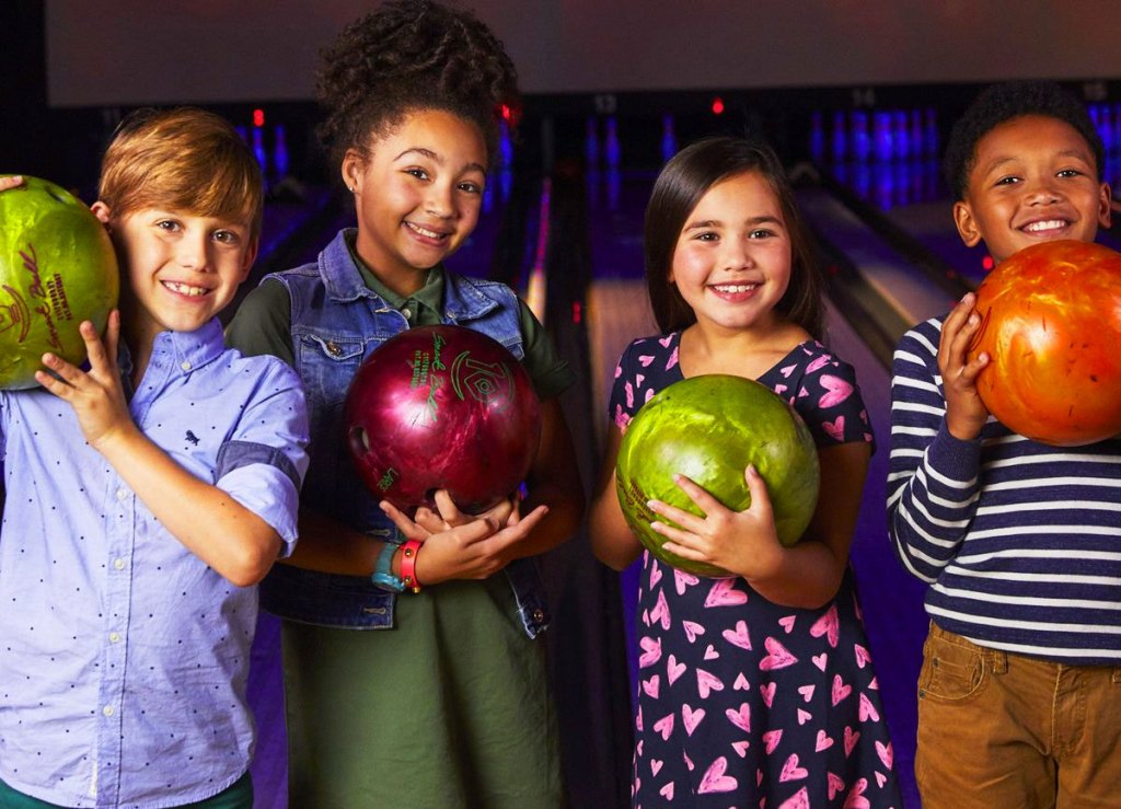 group of kids holding bowling balls