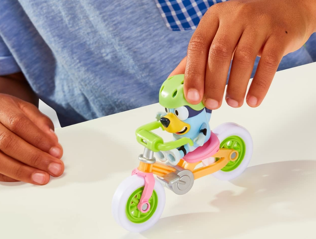 boy in a blue shirt playing with a Bluey figurine and Bicycle Toy