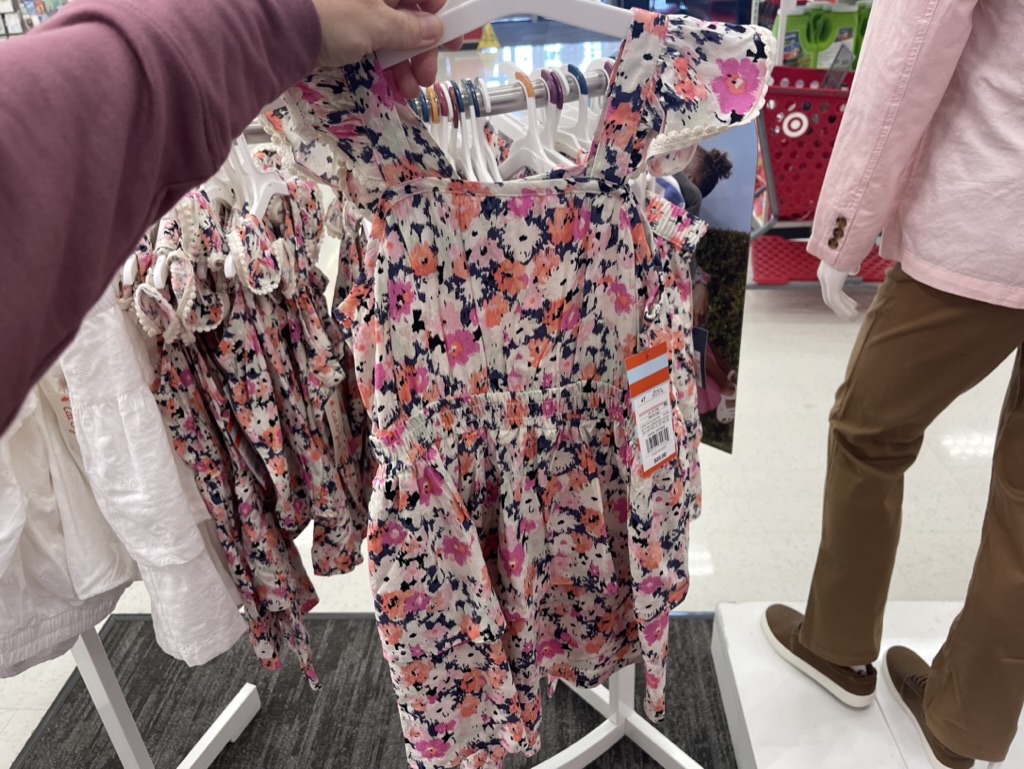 Hand holding a floral dress on a hanger