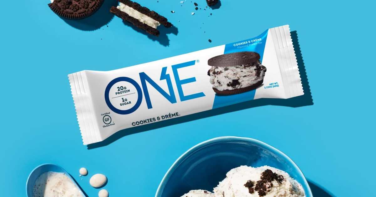 stock image of a Cookies & cream protein bar against a blue background with pieces of cookie and a bowl of ice cream