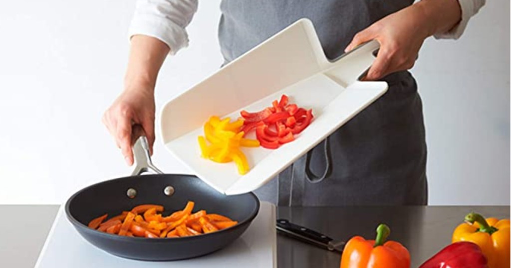 Chef using Chop2Pot Cutting Board to put peppers in pan