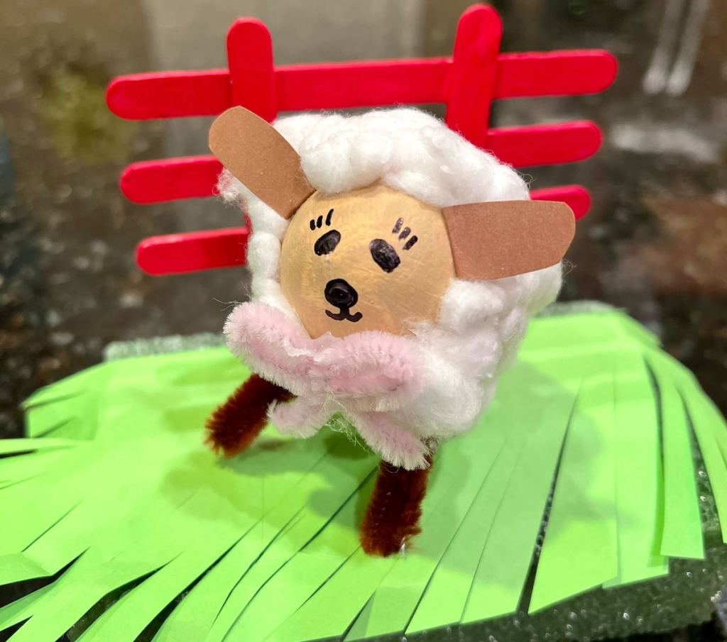 easter egg decorated into a sheep with grass and red fence