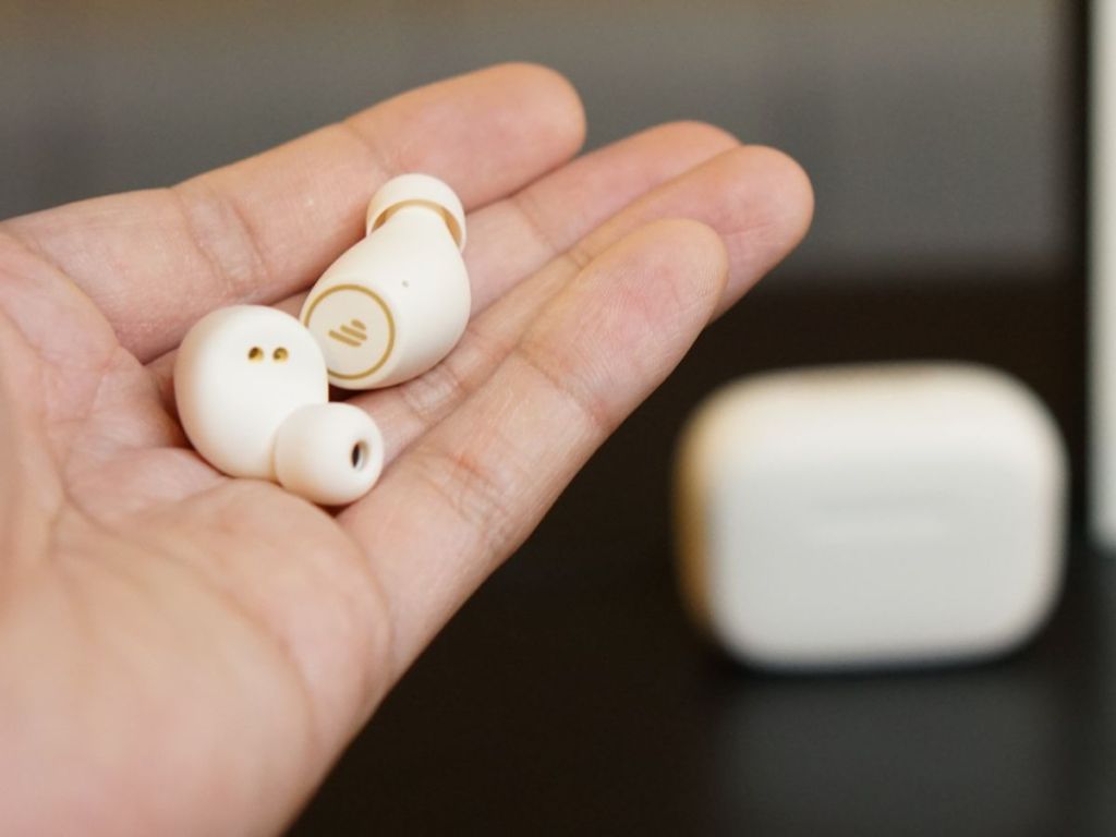 Hand holding Edifier Earbuds with charging case in the background