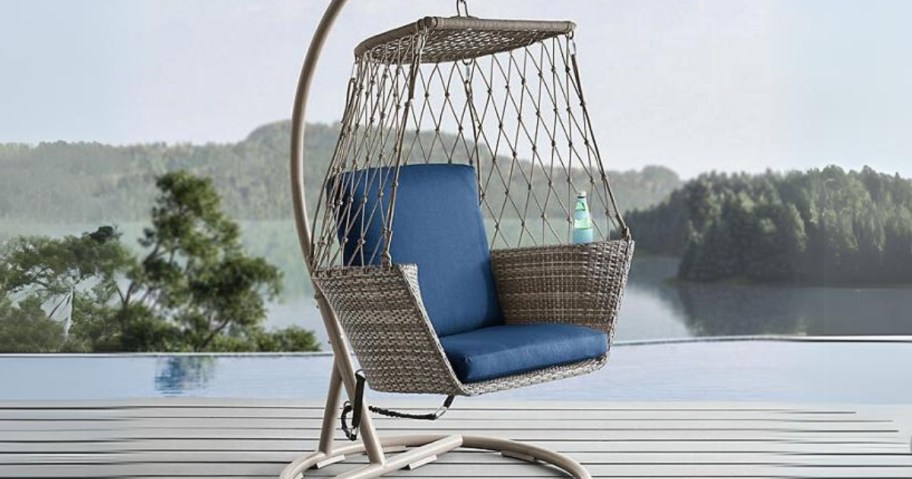 tan wicker and rope hanging chair on a steel frame by a pool