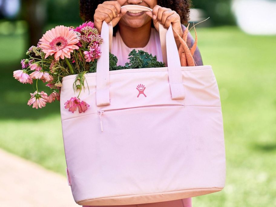 Woman holding pink Hydroflask cooler with flowers inside