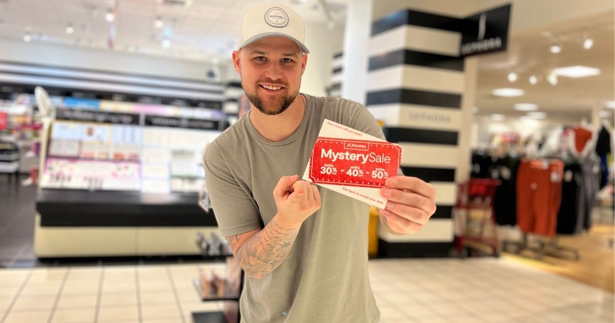 man holding up JCPenney Mystery Sale coupon