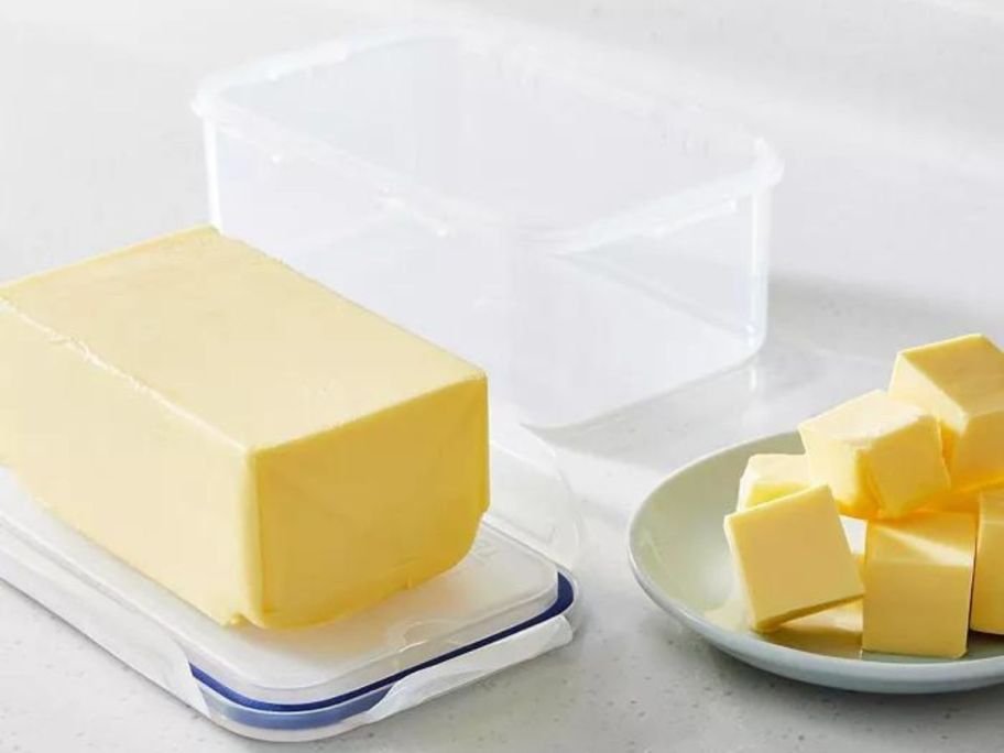 A lock n Lock butter container filled with a block of butter next to a plate of butter cut into chunks
