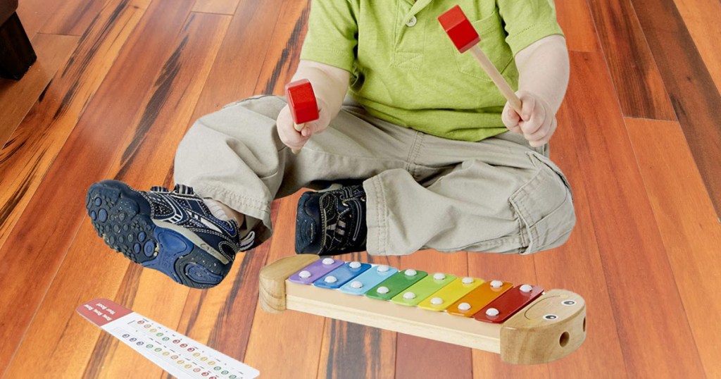 boy playing with xylophone on floor