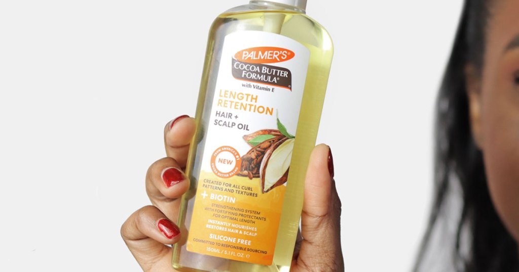 woman holding a bottle of Palmer's Cocoa Butter hair oil