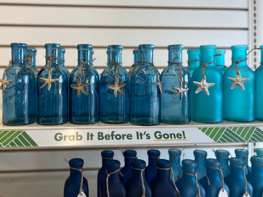 blue glass bottles with seashell charms on store shelf