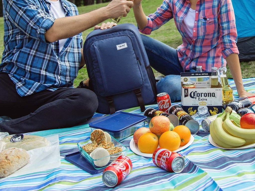 man taking beer out of cooler backpack on picnic