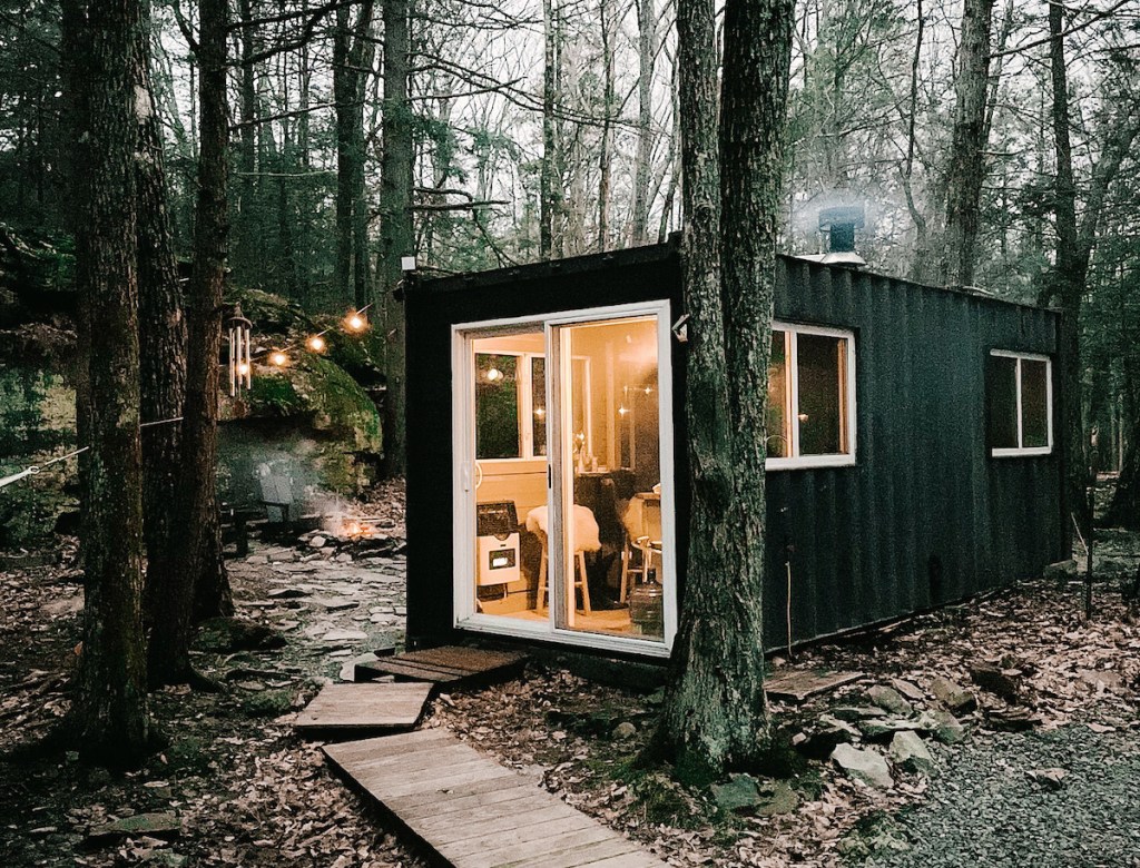black shipping container tiny home in woods