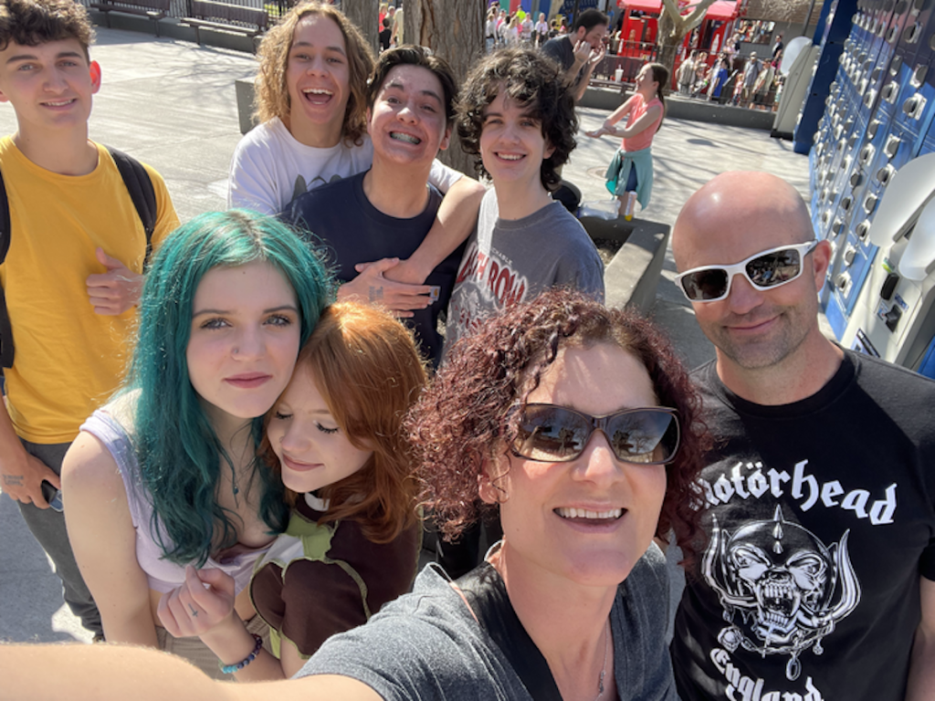 teens and parents smiling at camera at amusement park