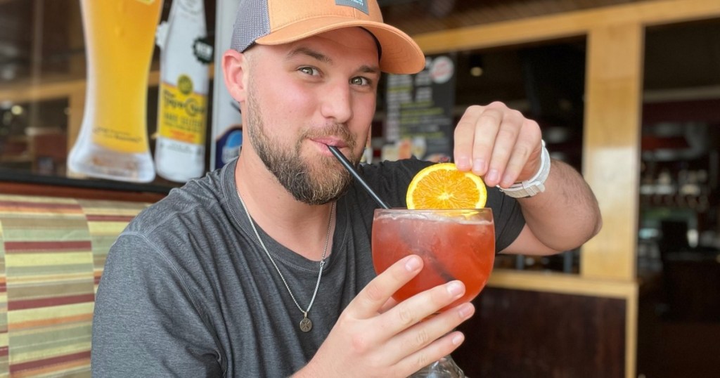 man sipping cocktail through a straw