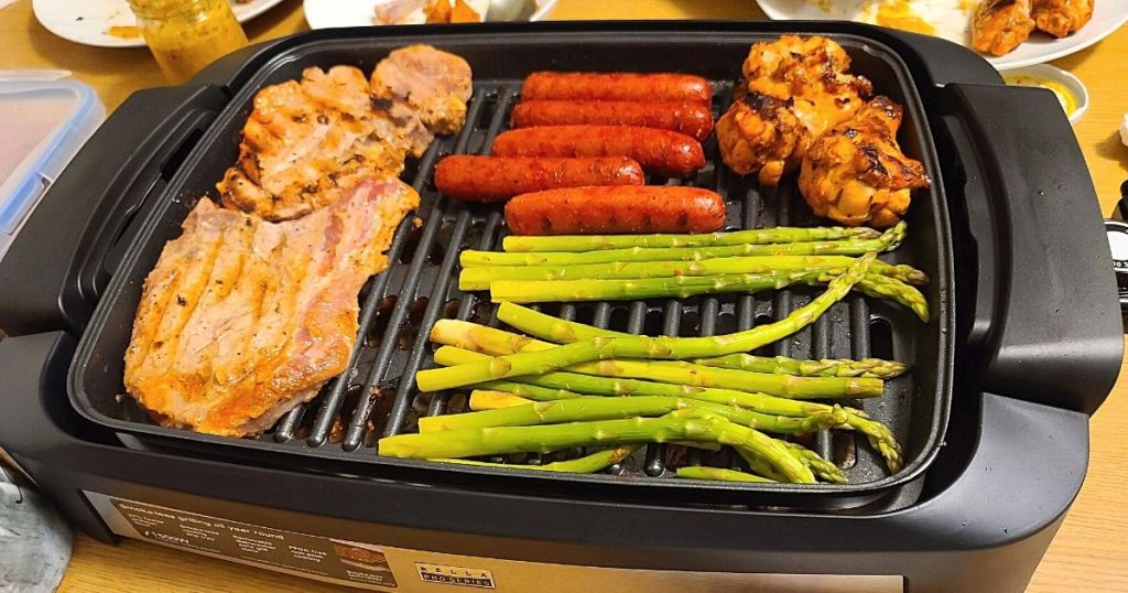meat and asparagus cooking on countertop grill