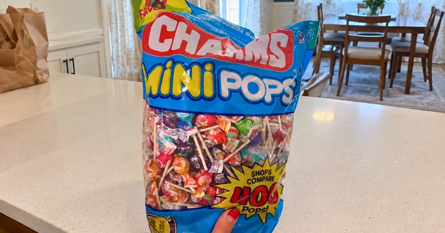 hand holding a bag of Charms mini lollipops in a kitchen