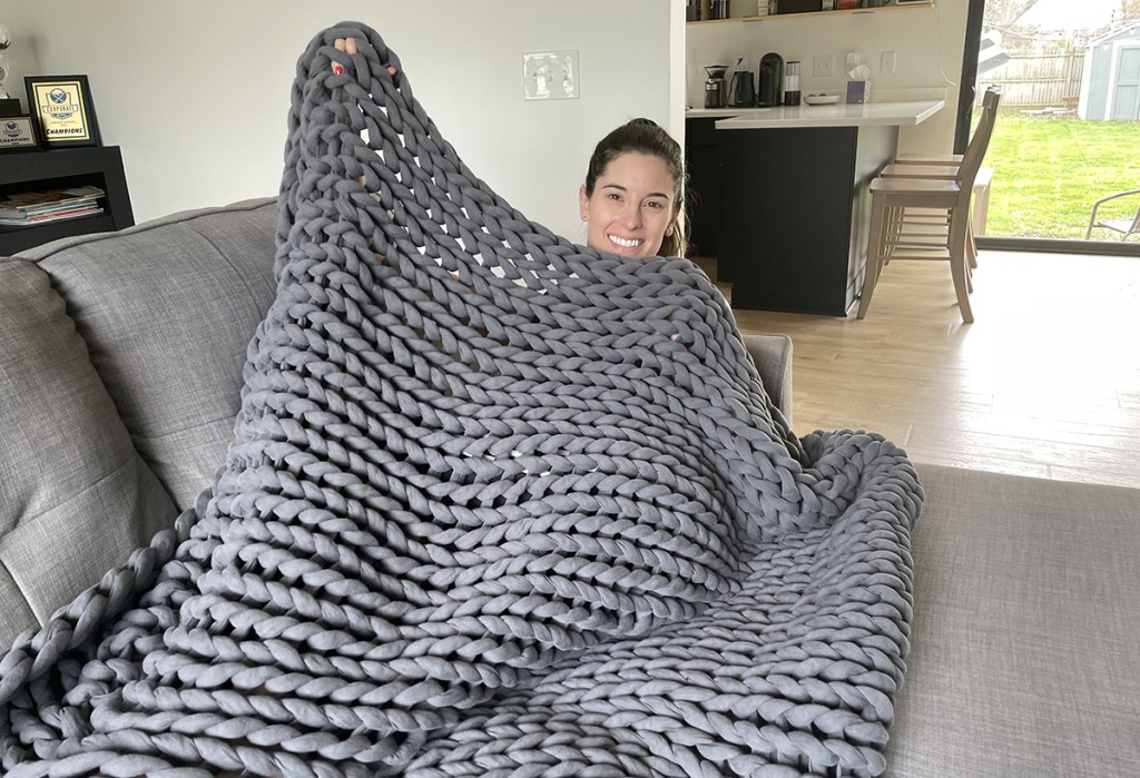 women underneath bearaby weighted blanket on couch